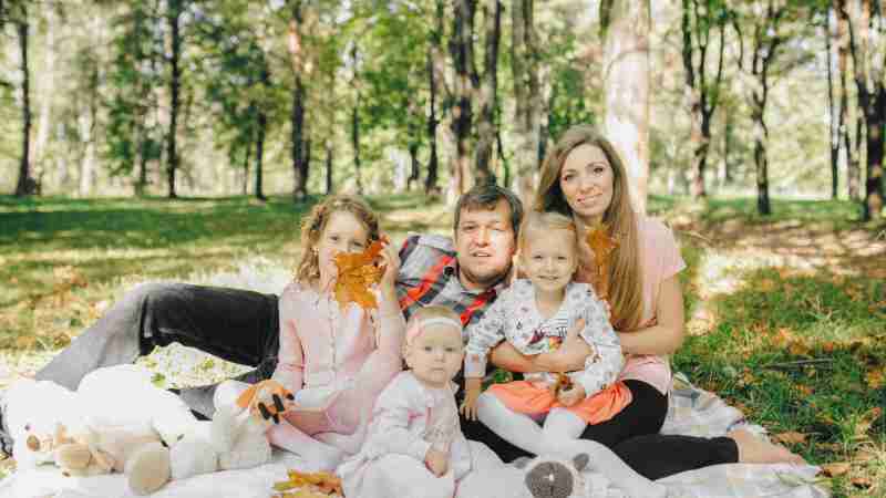Family of five enjoying an autumn picnic in a serene forest setting, radiating happiness., tags: und - pexel